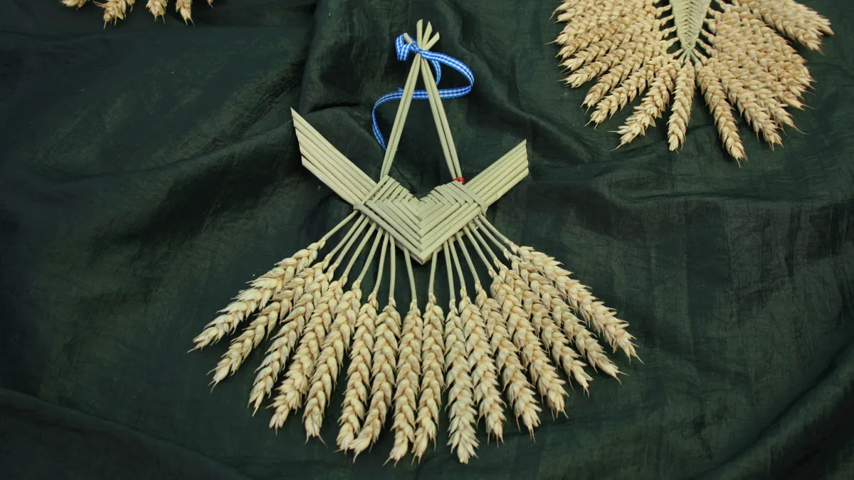 Woven wheat corn dollies and harvest knots at a German market Harvest traditions in straw: woven wheat corn dollies and harvest knots laid out on a green cloth at a craft market