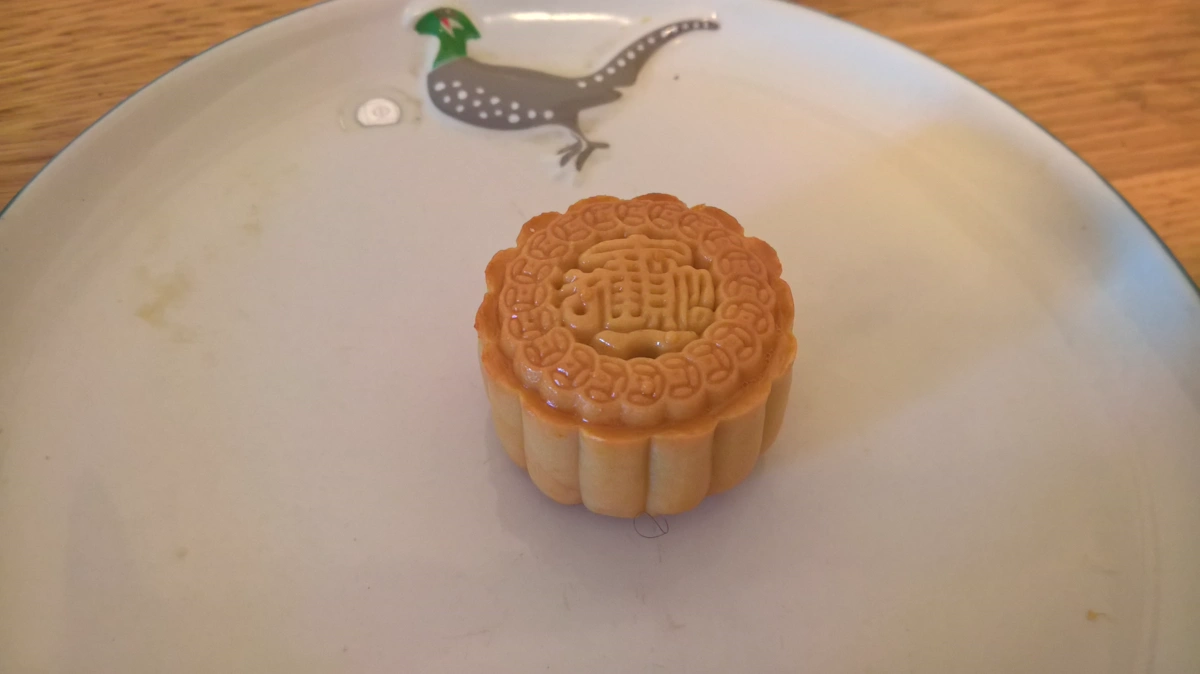 Mooncake for the Vietnamese Mid-Autumn Festival, Tet Trung Thu A single pressed mooncake with a stamped pattern on a white plate, made for the Vietnamese mid-autumn moon festival