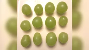 Twelve green grapes laid out in three rows on a white plate, one for each month of the coming year