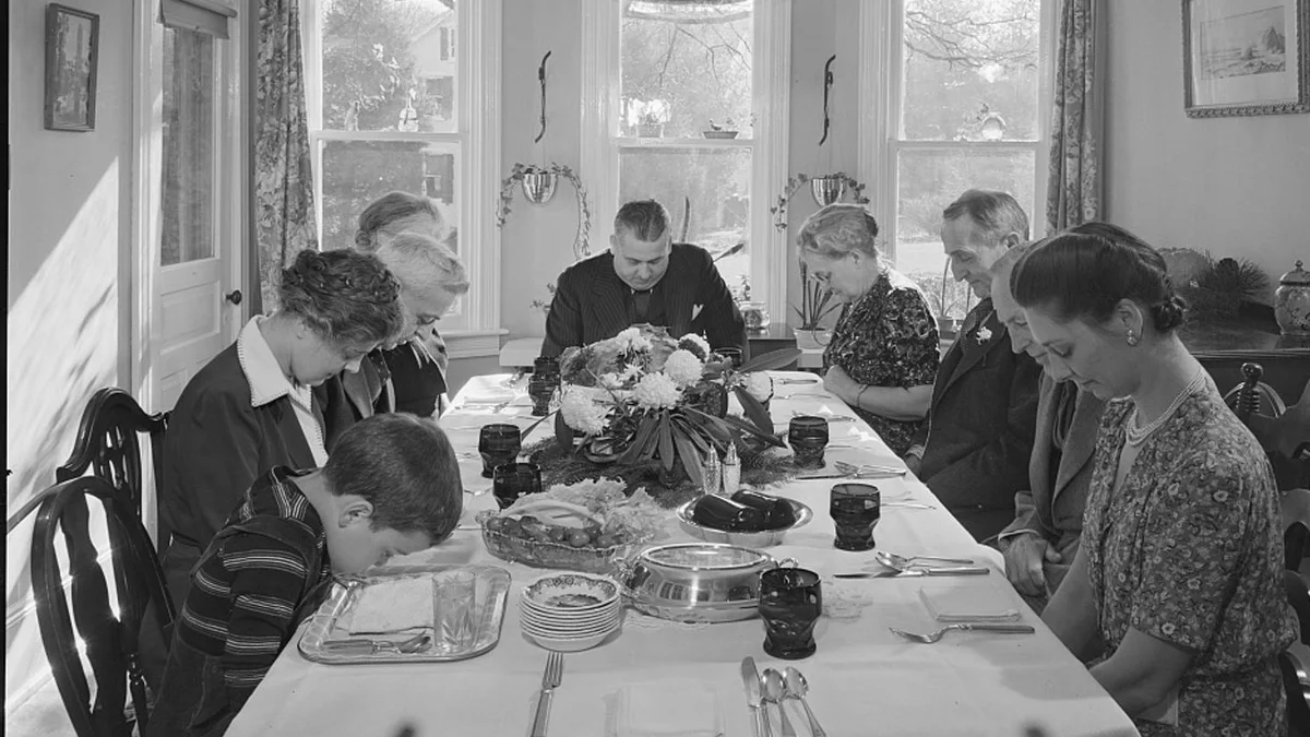Grace before the turkey at a 1942 Thanksgiving dinner in Pennsylvania Thanksgiving dinner traditions in 1942: a family bows heads for grace at a long table set with a flower centerpiece in Neffsville, Pennsylvania